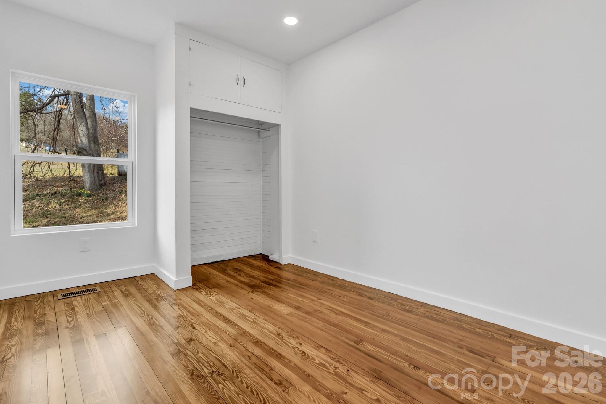 246 Marion Street Marion, NC 28752 - Photo 24 of 48 a view of an empty room with wooden floor and a window