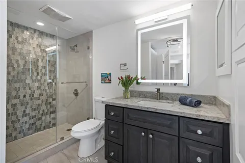 a bathroom with a granite countertop toilet sink and mirror