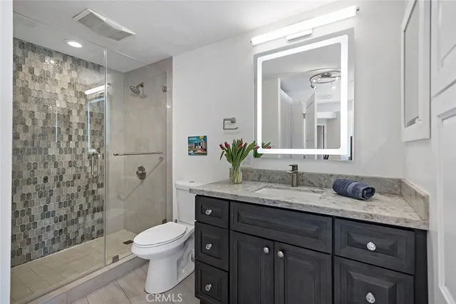 a bathroom with a granite countertop toilet sink and mirror