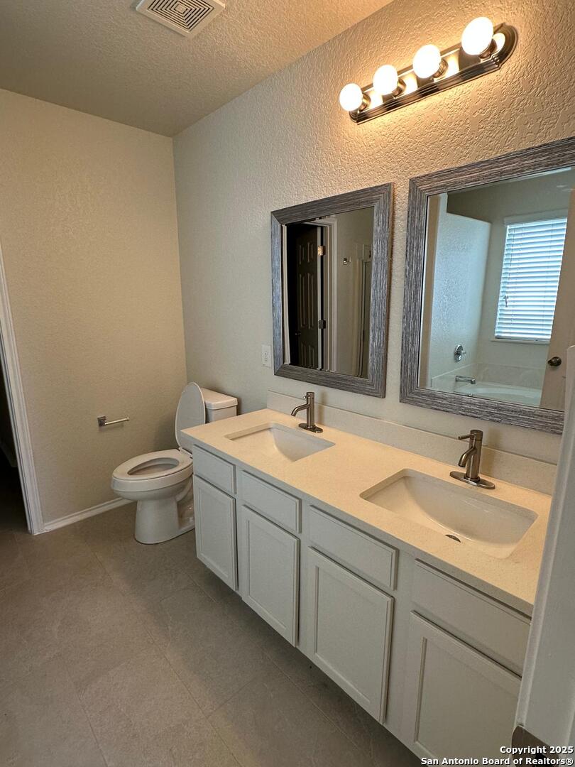 25346 Colt River San Antonio, TX 78261 - Photo 18 of 35 a bathroom with a double vanity sink mirror and toilet
