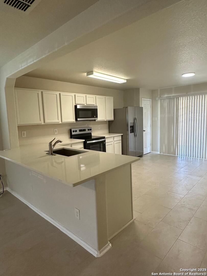 25346 Colt River San Antonio, TX 78261 - Photo 2 of 35 a kitchen with kitchen island white cabinets and refrigerator