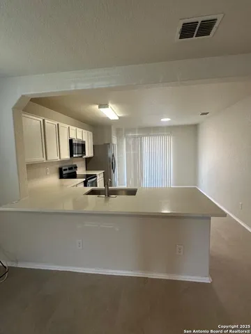 a view of kitchen with stainless steel appliances granite countertop white cabinets and a refrigerator