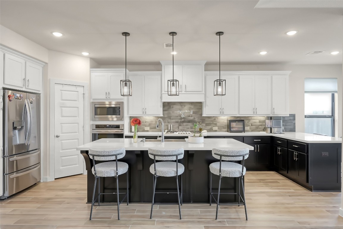 6718 Waxbill Road Katy, TX 77493 - Photo 10 of 48 a kitchen with stainless steel appliances kitchen island granite countertop a dining table chairs and sink