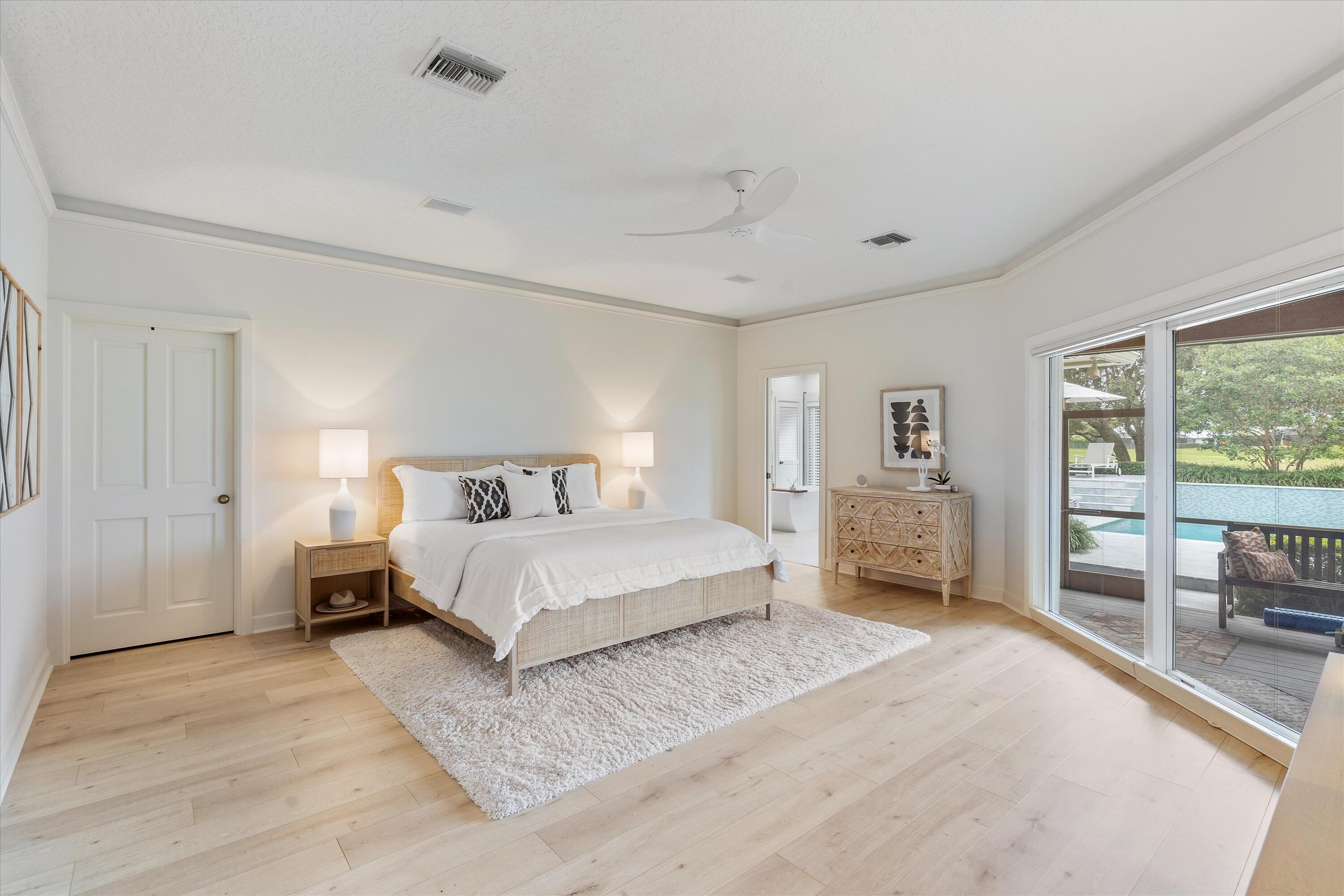 121 Turnberry Drive Atlantis, FL 33462 - Photo 19 of 47 a spacious bedroom with a bed a table and a large window