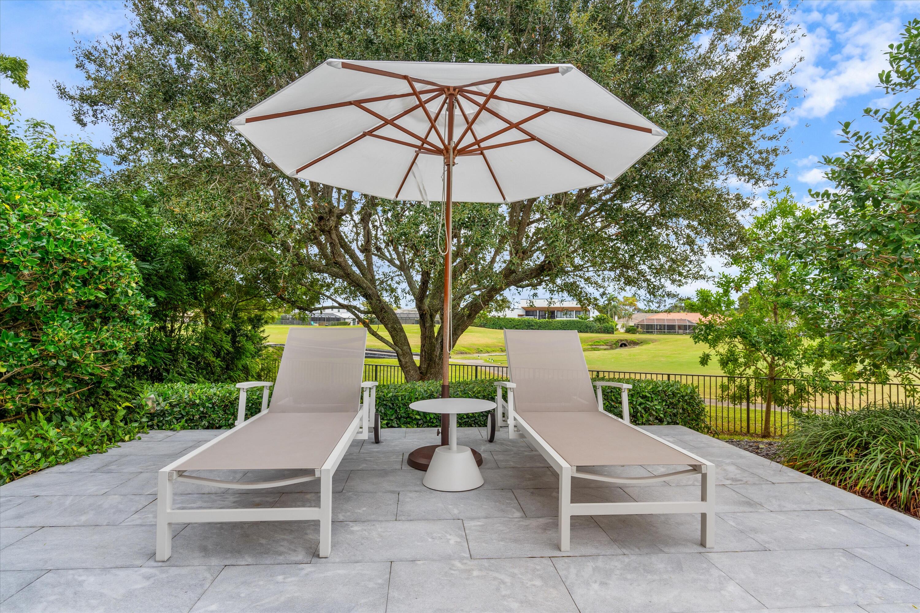 121 Turnberry Drive Atlantis, FL 33462 - Photo 35 of 47 a view of a patio with a table and chairs under an umbrella