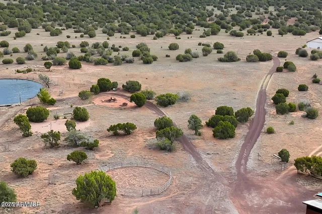 a view of a patio with lawn chairs under wooden roof with potted plants