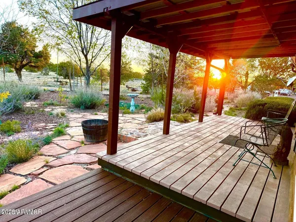 a view of a patio with lawn chairs under wooden roof with potted plants