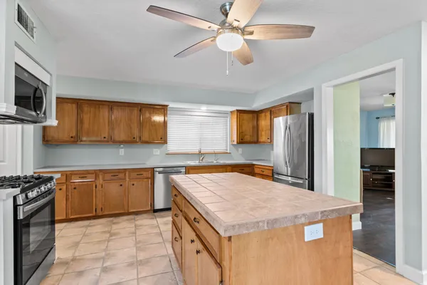 a large kitchen with stainless steel appliances a stove a refrigerator a sink dishwasher with a dining table and chairs