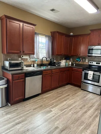 a kitchen with stainless steel appliances granite countertop a sink a stove and wooden cabinets