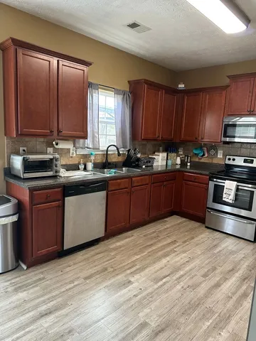 a kitchen with stainless steel appliances granite countertop a sink a stove and wooden cabinets