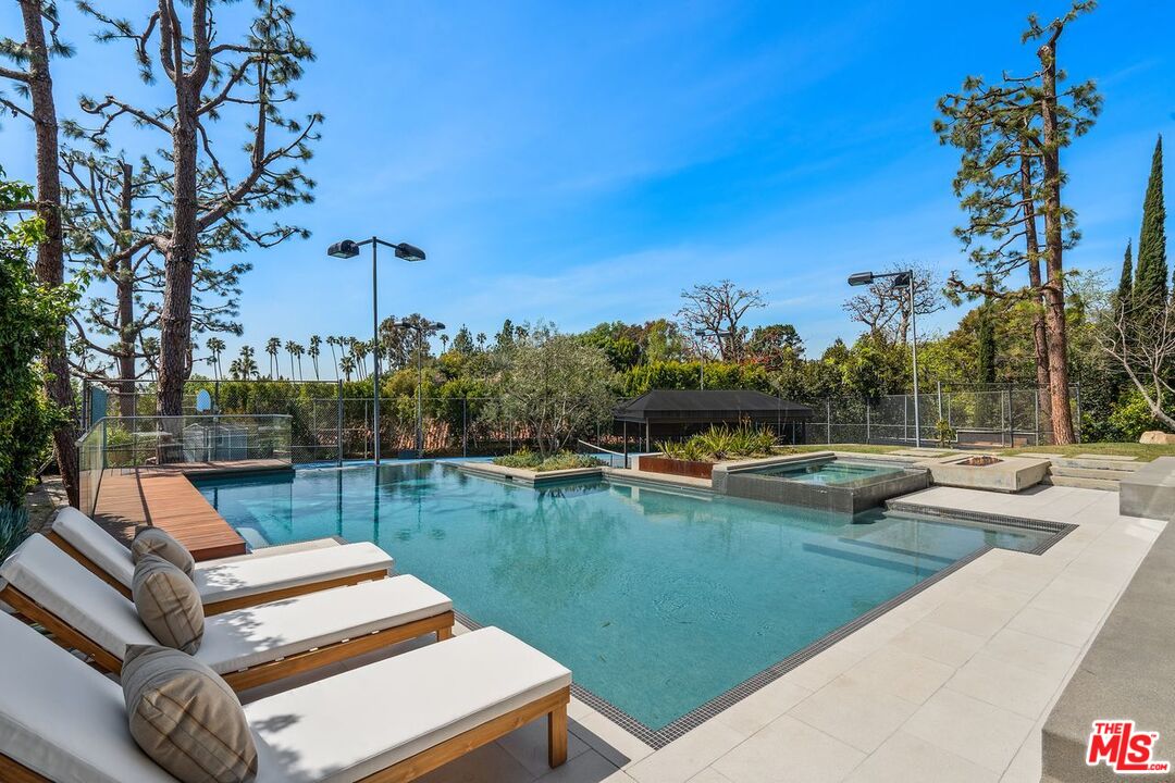 1005 Elden Way Beverly Hills, CA 90210 - Photo 50 of 62 a view of a swimming pool with couches and a table and chairs under an umbrella