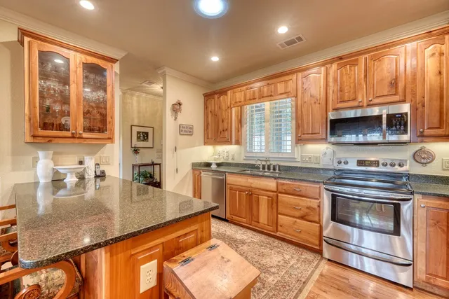 a kitchen with stainless steel appliances granite countertop a stove a sink and a microwave