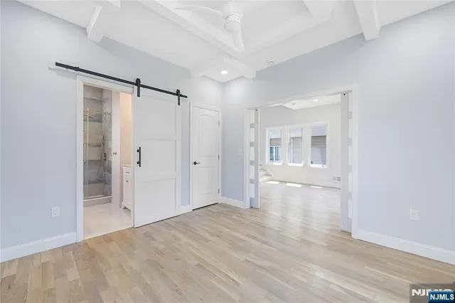 a view of an empty room with wooden floor and a bathroom