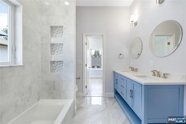 a bathroom with a double vanity sink mirror and bathtub