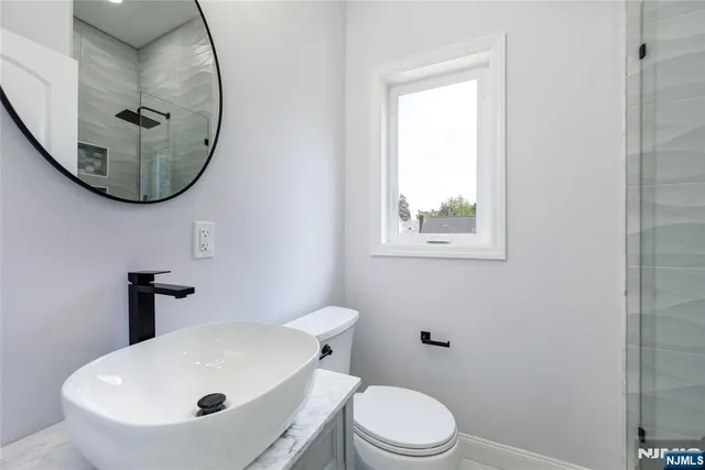 a bathroom with a sink a mirror a toilet and a window