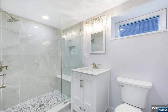 a bathroom with a sink a toilet a mirror and shower