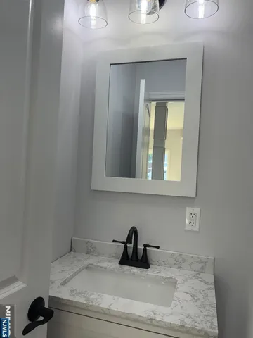 a bathroom with a granite countertop sink and a mirror