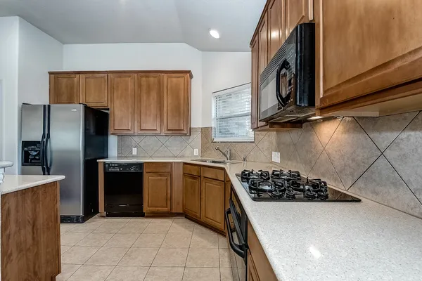 a kitchen with stainless steel appliances granite countertop a stove a sink dishwasher and a refrigerator