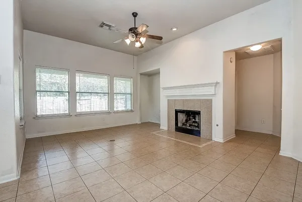 an empty room with chandelier fan and windows