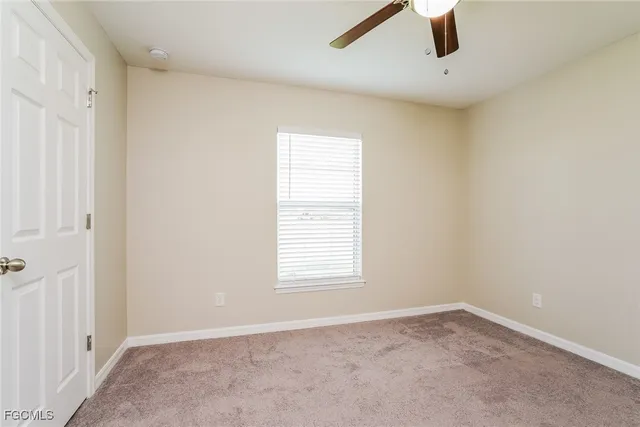 an empty room with a window and a ceiling fan