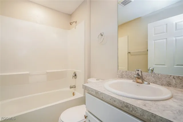 a bathroom with a granite countertop sink a toilet and bathtub