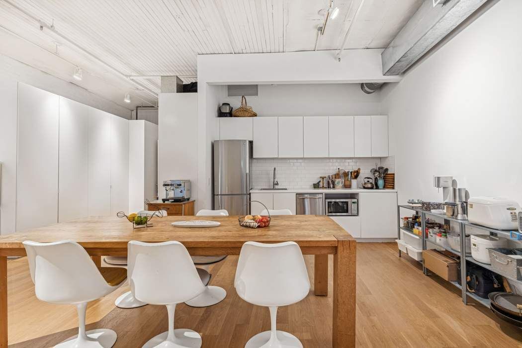 97 Crosby Street, Unit 1 Manhattan, NY 10012 - Photo 6 of 15 a room with stainless steel appliances kitchen island granite countertop a dining table chairs and a refrigerator