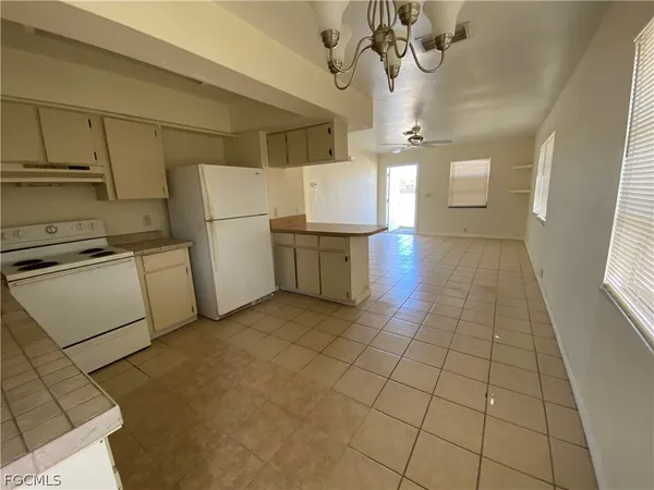 a view of a kitchen with a sink and dishwasher a refrigerator with white cabinets