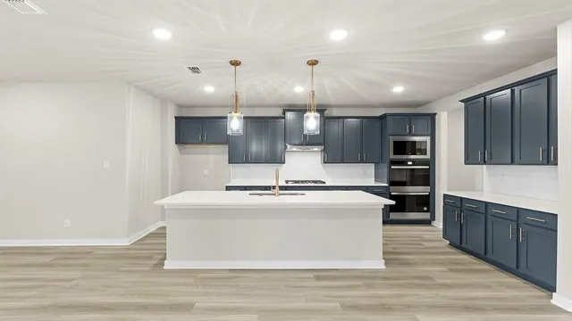 a large kitchen with stainless steel appliances a large counter top and wooden floors