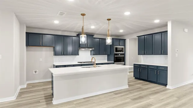 a large kitchen with stainless steel appliances kitchen island a large counter top and wooden cabinets