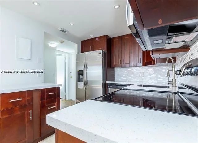 a kitchen with stainless steel appliances a sink a stove a refrigerator and cabinets