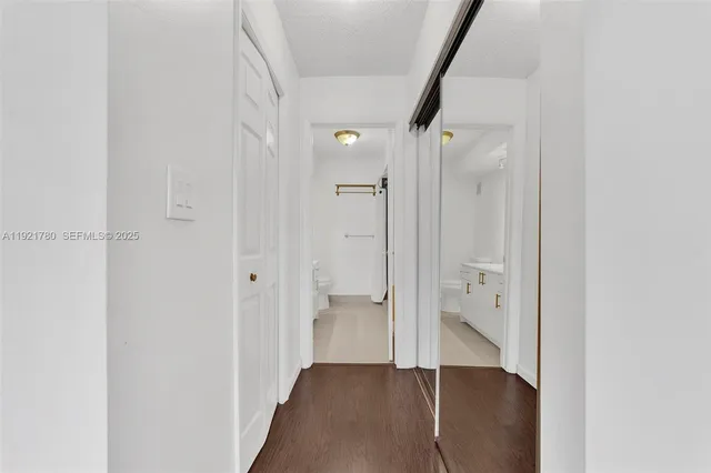 an empty room with wooden floor and a bathroom view