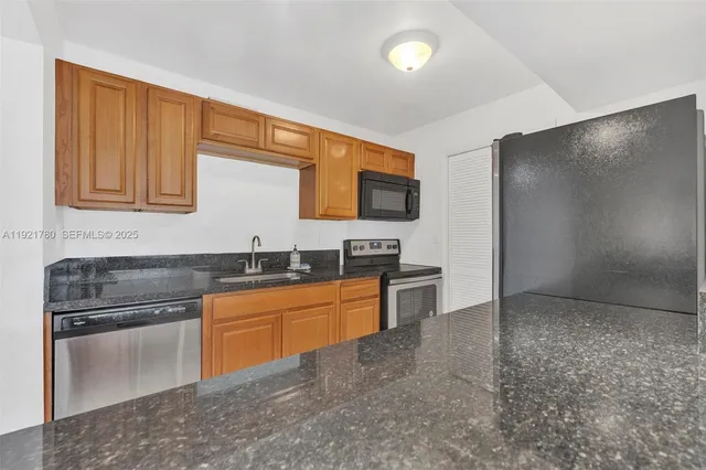 a kitchen with granite countertop a sink stainless steel appliances and cabinets