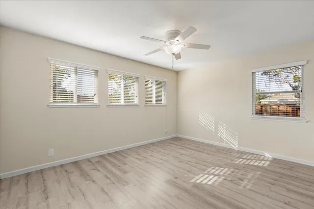 a view of an empty room with a window and wooden floor