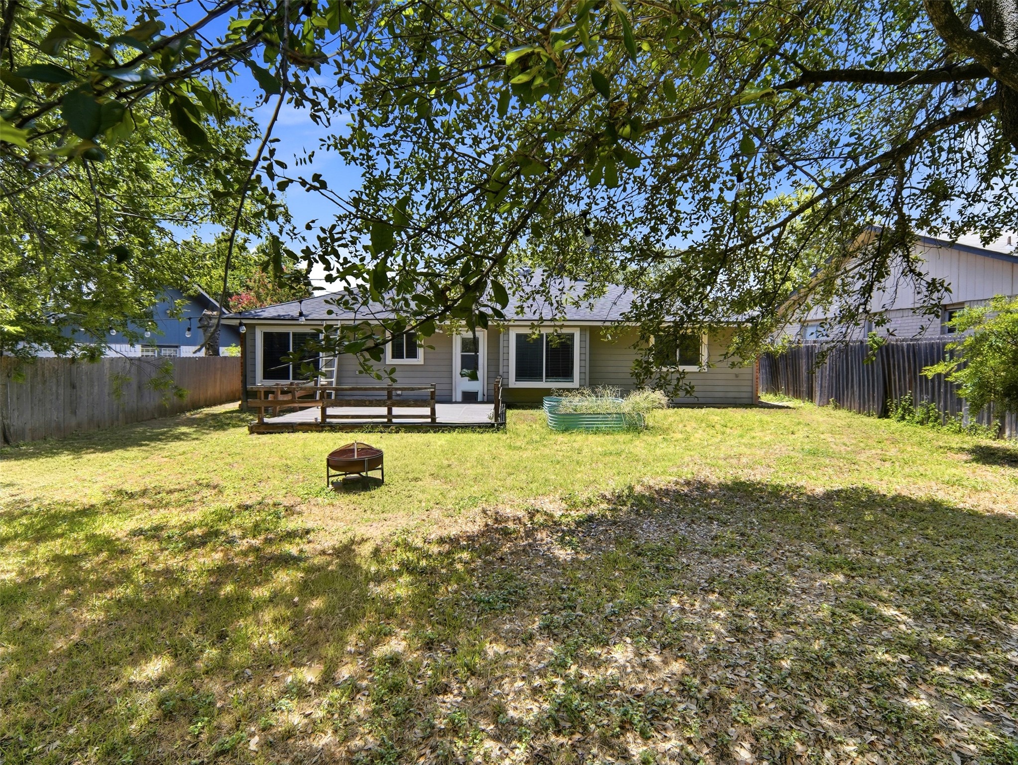 7001 Windrift Way Austin, TX 78745 - Photo 16 of 17 A spacious yard with a wooden deck and fire pit, perfect for outdoor living.