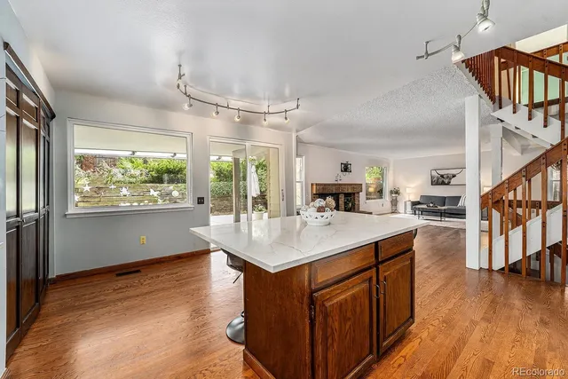 a room with kitchen island a large counter top space a sink a refrigerator and windows