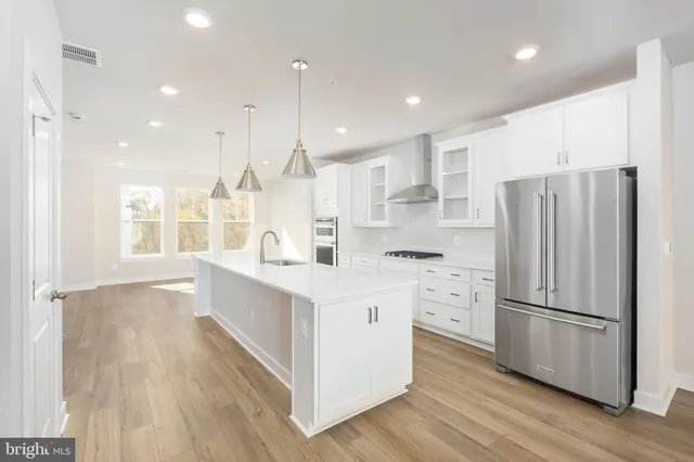 a large kitchen with stainless steel appliances sink a microwave and wooden floor