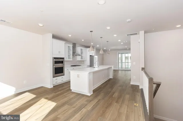 a large white kitchen with a stove a sink dishwasher and a refrigerator with wooden floor