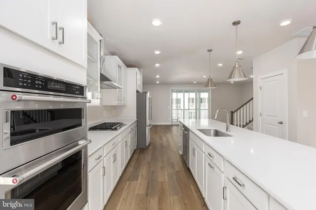 a kitchen with counter top space stainless steel appliances and wooden floor