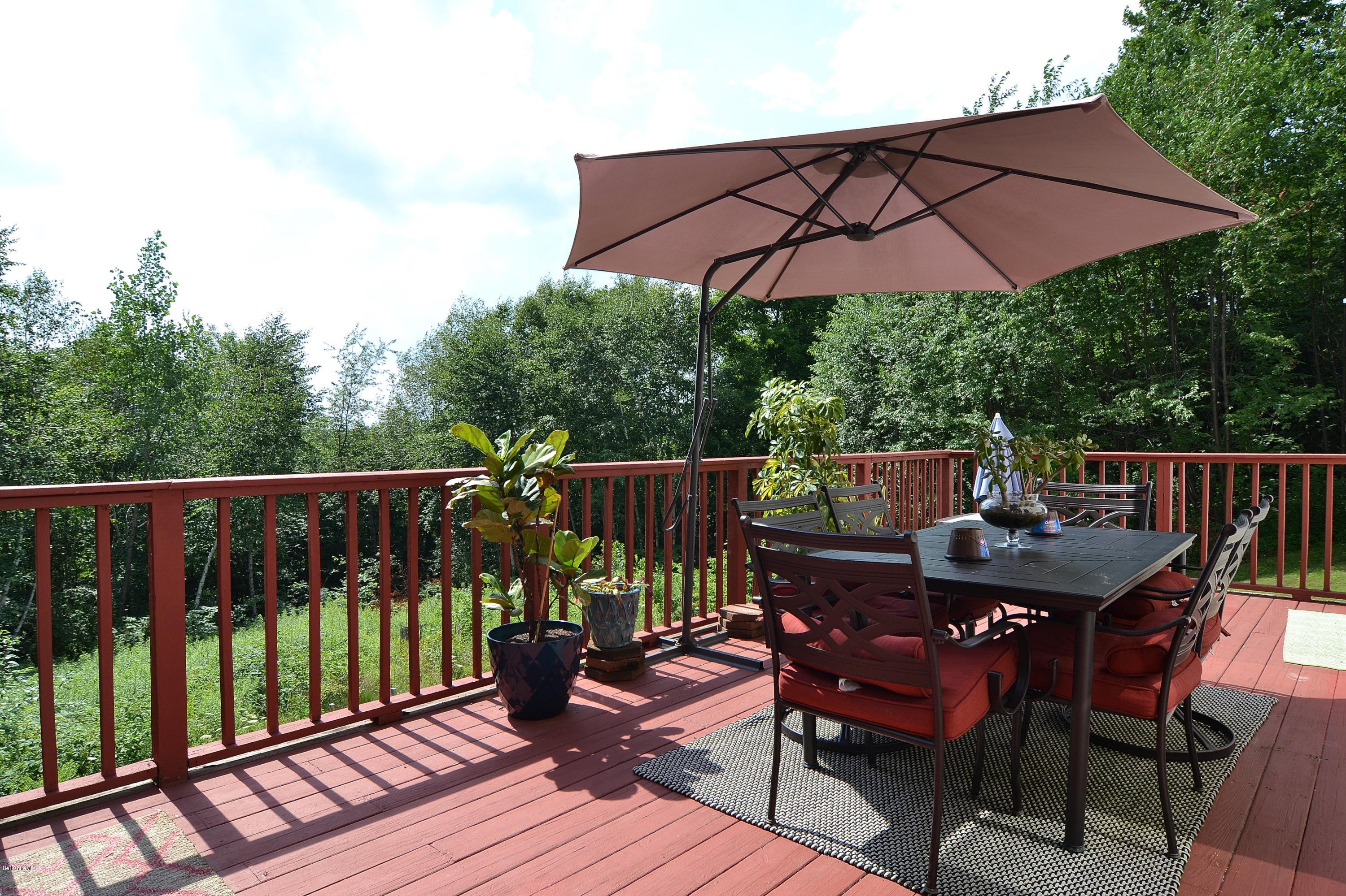 693 George Carter Road Becket, MA 01223 - Photo 16 of 36 a patio with wooden floor a yard a table and chairs