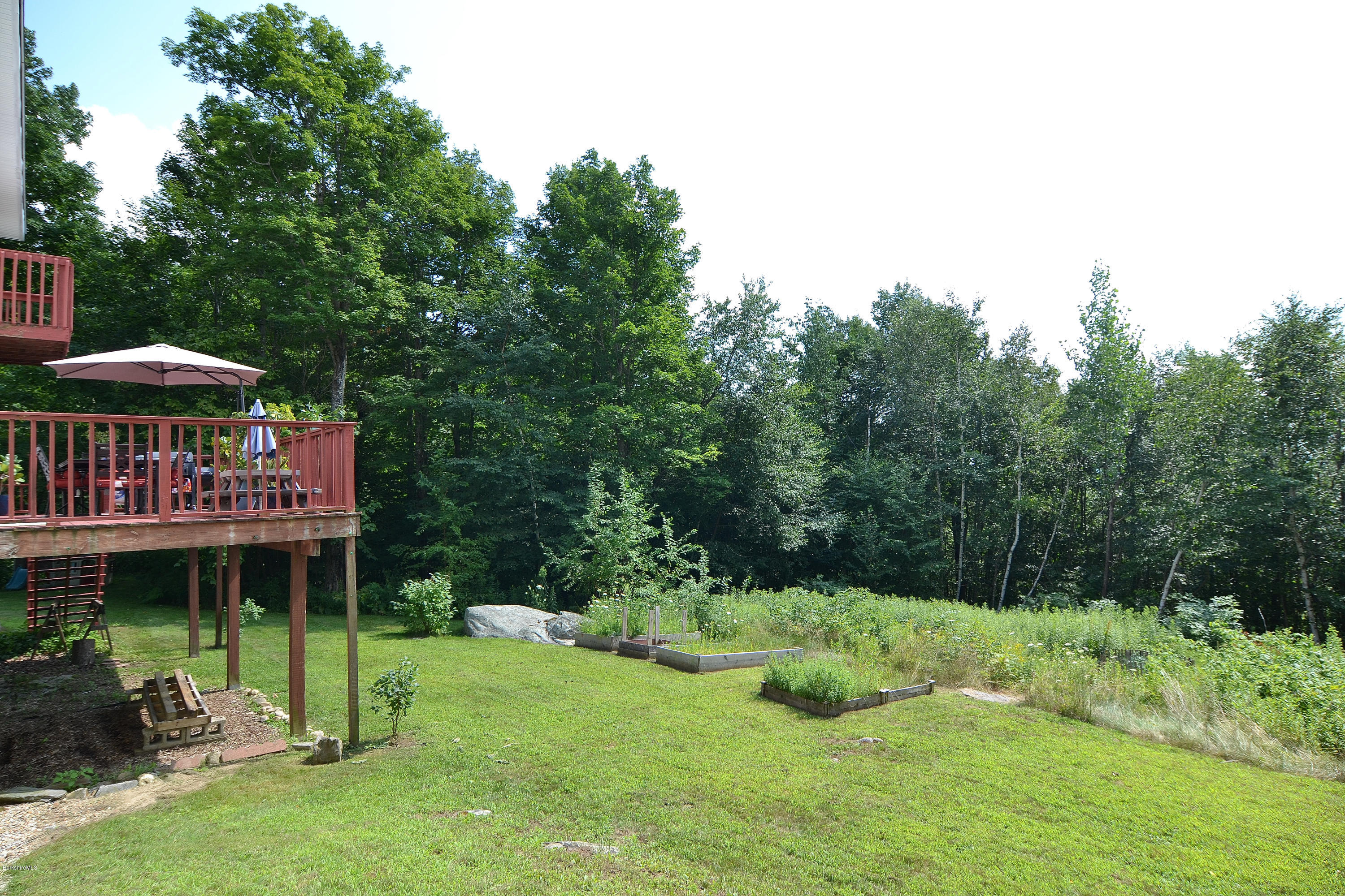 693 George Carter Road Becket, MA 01223 - Photo 35 of 36 a view of patio with a table and chairs under an umbrella