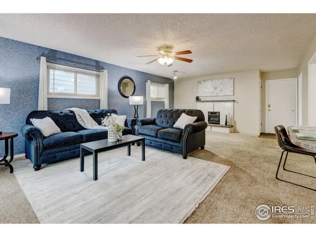 a living room with furniture a clock on wall and a window