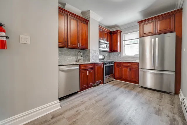 a kitchen with stainless steel appliances granite countertop a refrigerator a sink dishwasher a stove with wooden cabinets and floor