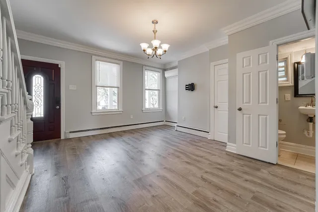 an empty room with wooden floor chandelier and windows
