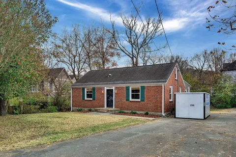 a view of a house with a yard and large tree
