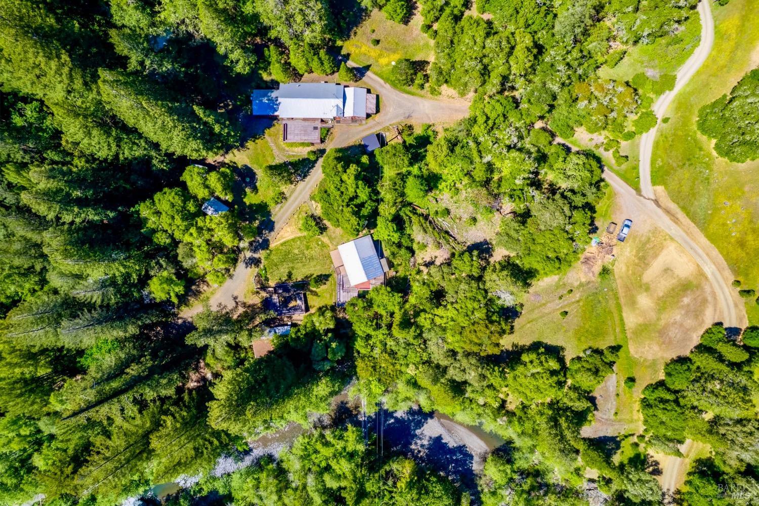Birds Eye view of retreat center rimmed in redwood trees and open meadows with the river flowing below