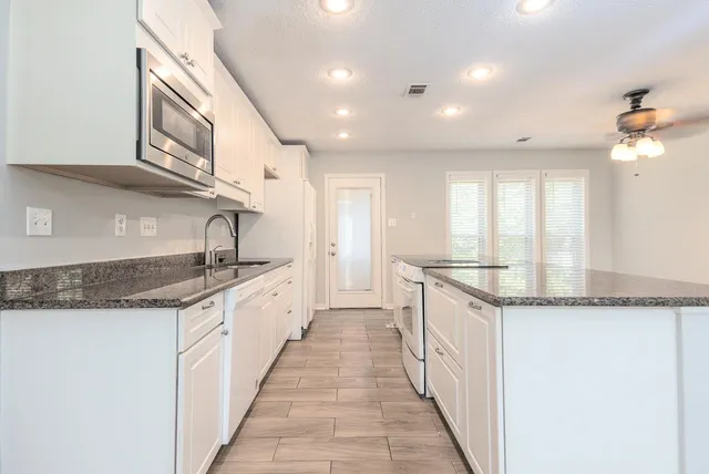 a large kitchen with stainless steel appliances granite countertop a sink and dishwasher