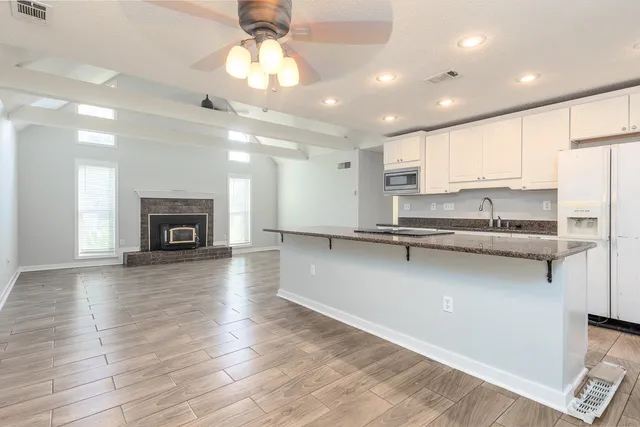a view of an empty room with wooden floor fireplace and a window
