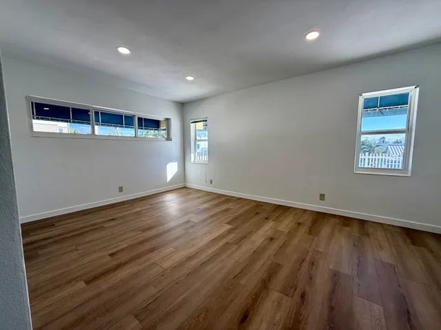 an empty room with wooden floor and windows