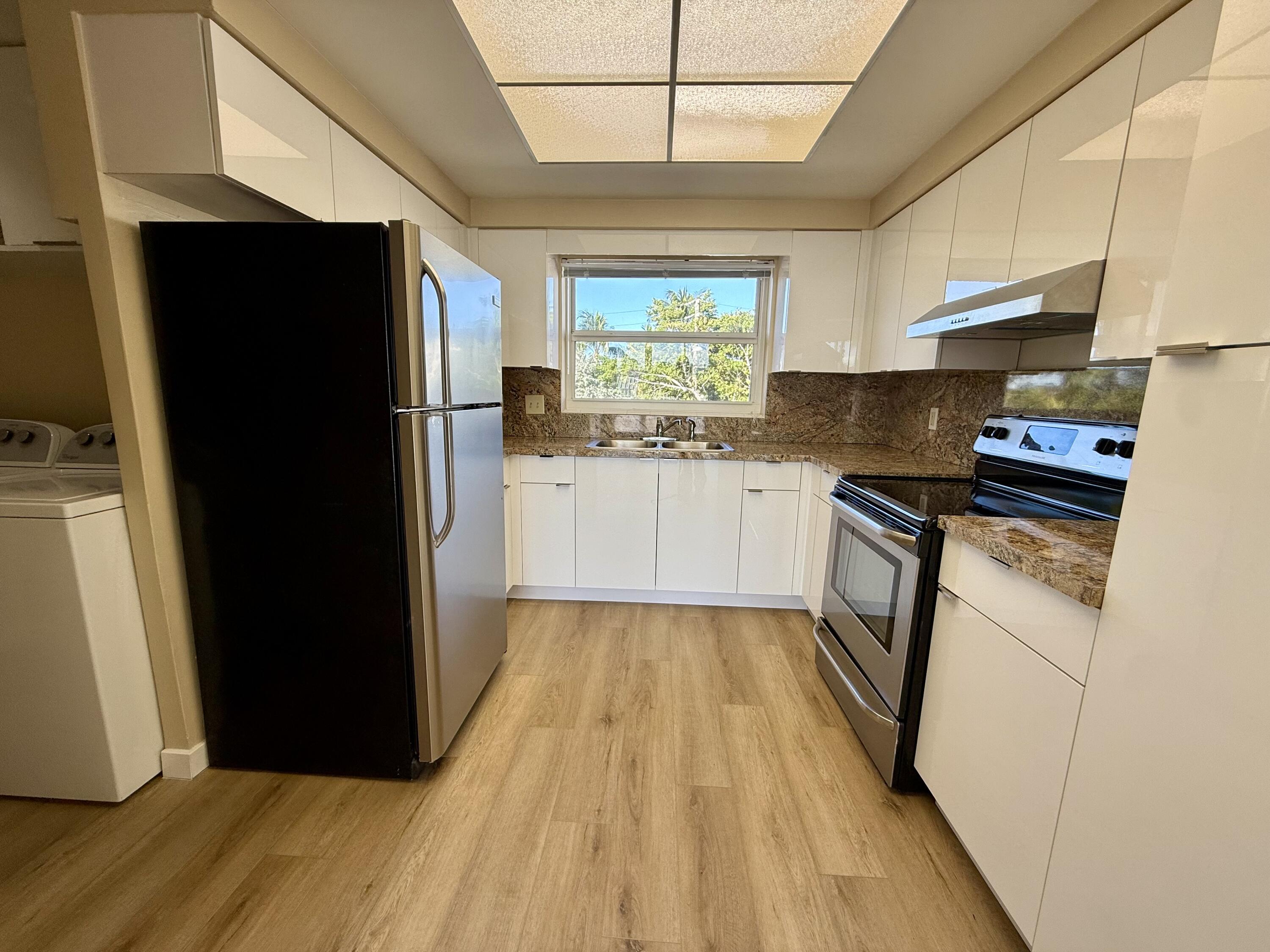 1165 East Atlantic Avenue, Unit A Delray Beach, FL 33483 - Photo 4 of 30 a kitchen with a refrigerator a stove top oven a sink and dishwasher with wooden floor