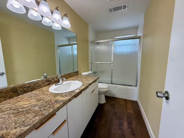 a bathroom with a granite countertop sink a large mirror and a toilet
